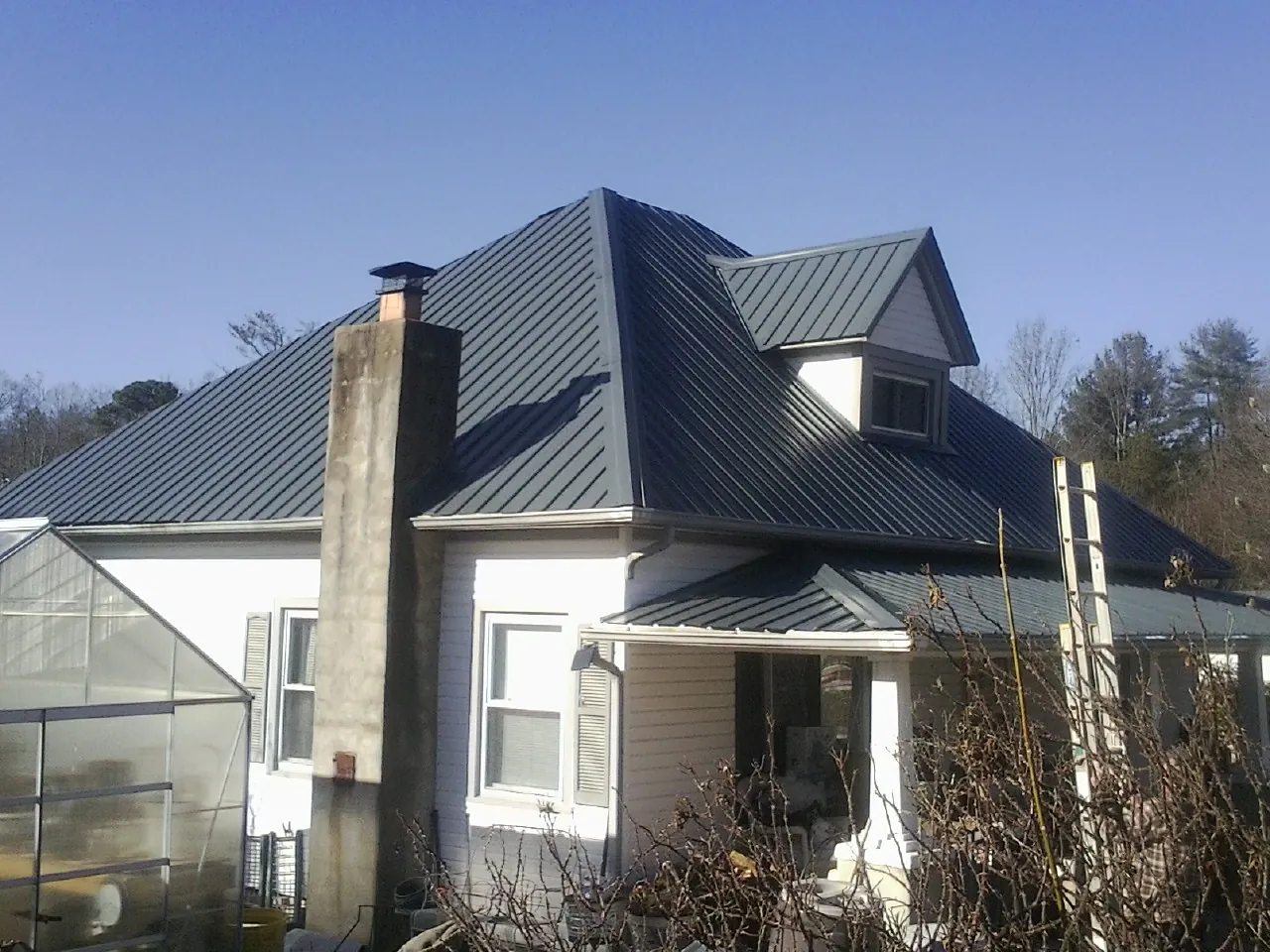 Dark blue standing seam metal roof on a white farmhouse with dormer — Slate & Tile Roof Repair by Roofing Brothers in Saco