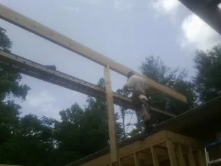 Carpenter setting a ridge beam over a new addition frame — Ice Dam Removal by Roofing Brothers in Saco