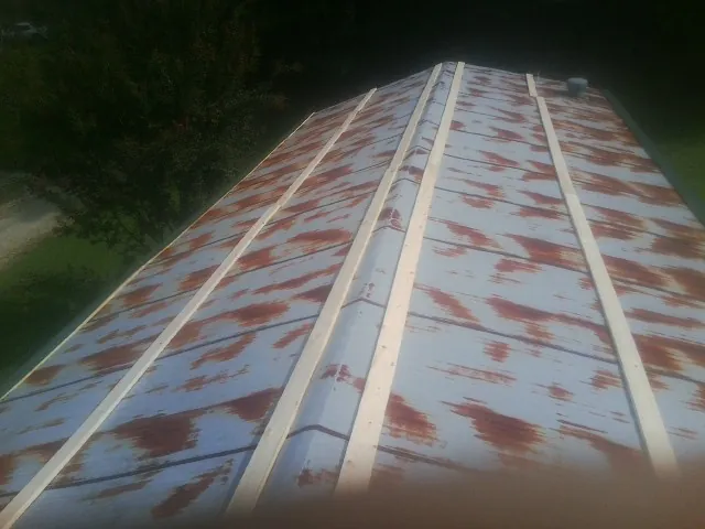 Rusted metal roof panels with new wood purlins before replacement in Saco