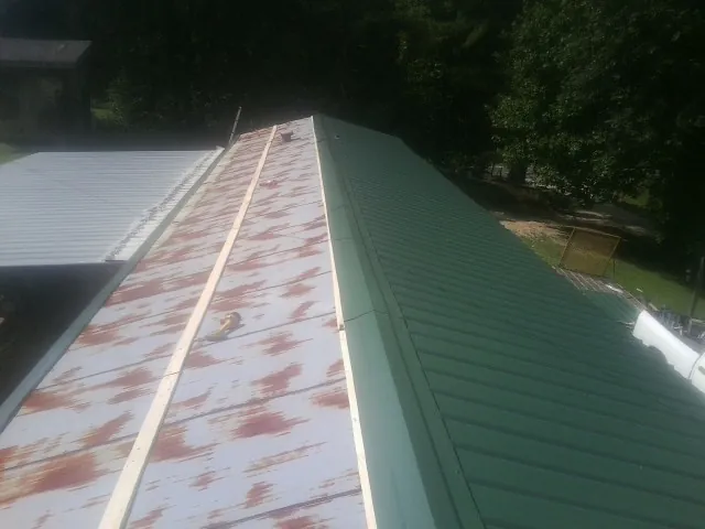 Old rusted panels beside newly installed green metal roofing — Wind Damage Roof Repair by Roofing Brothers in Saco