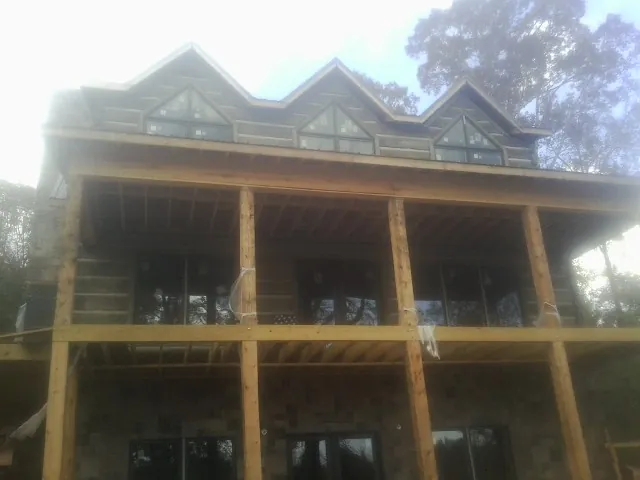 Dormers and porch framing on a large log home under construction — Roof Coating work by our crew in Saco