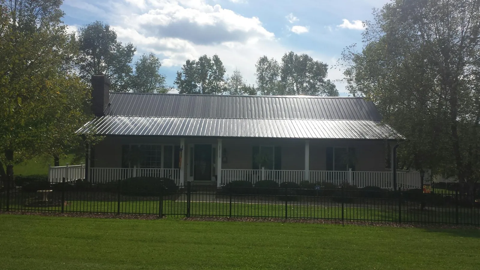 Gray metal roof on a brick ranch with a full width front porch — Gutter Guard Installation work by our crew in Saco