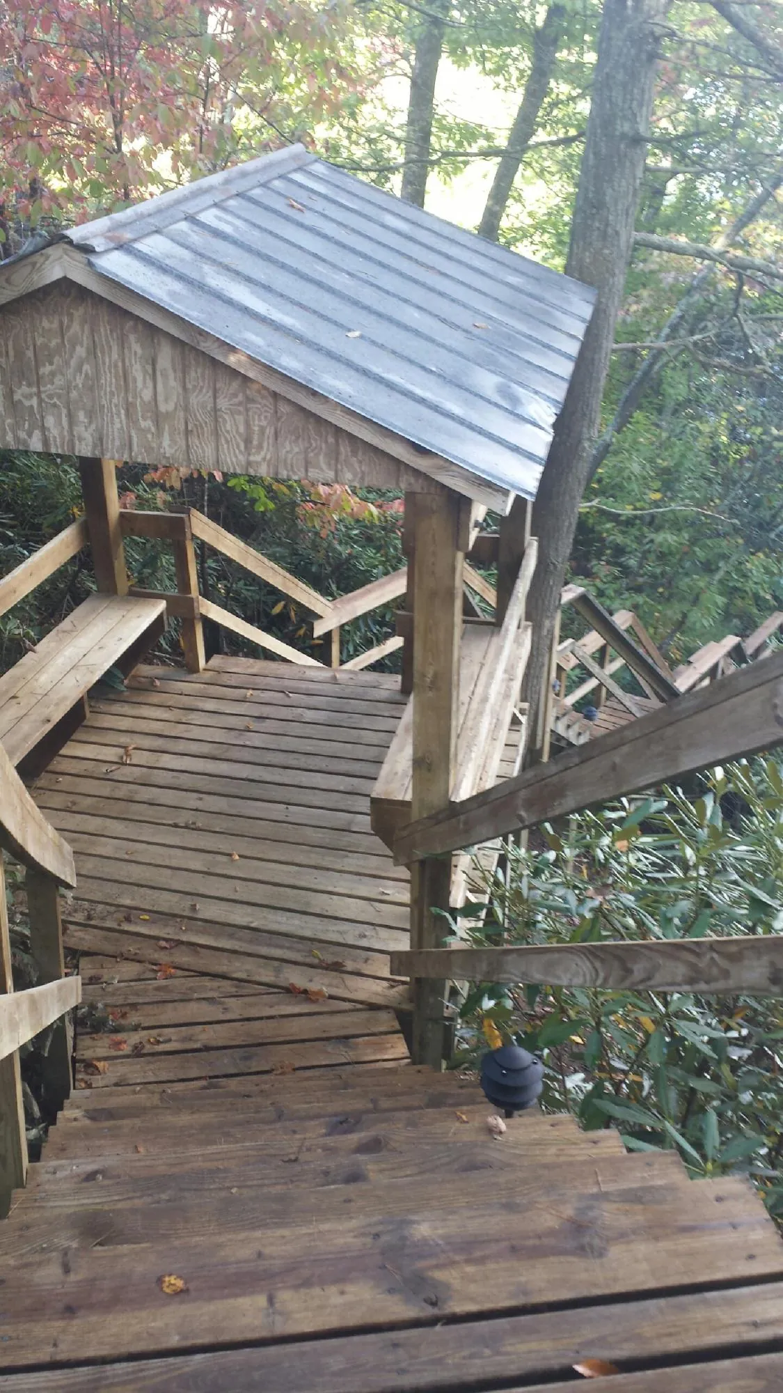 Metal roofed shelter over wooden steps on a wooded walkway — Skylight Repair & Installation work by our crew in Saco