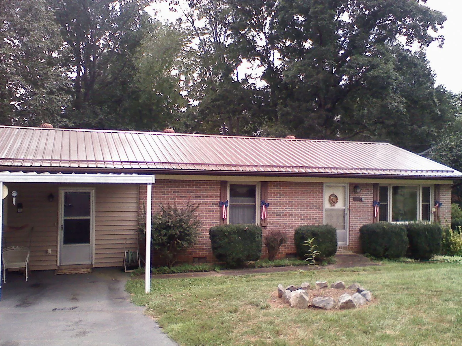 Bronze metal roof and carport on a brick ranch home — Roof Repair work by our crew in Saco