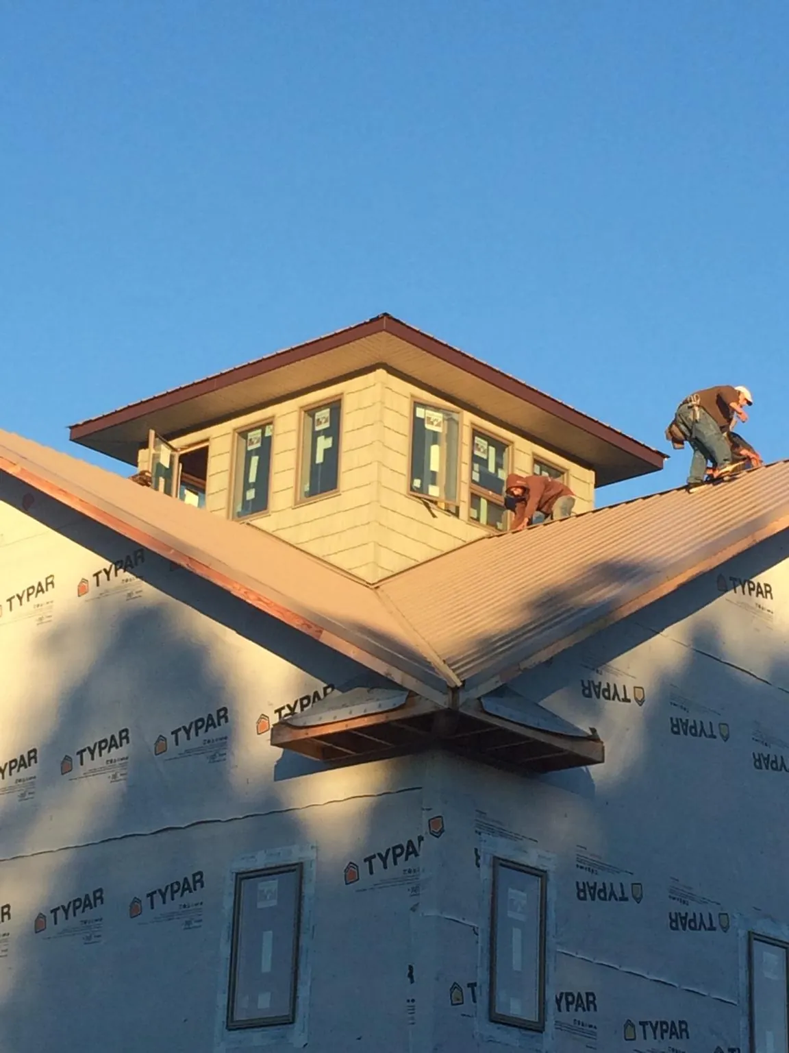 Roofers working around a rooftop cupola on a new metal roof at sunset — Roof Waterproofing in Saco by Roofing Brothers